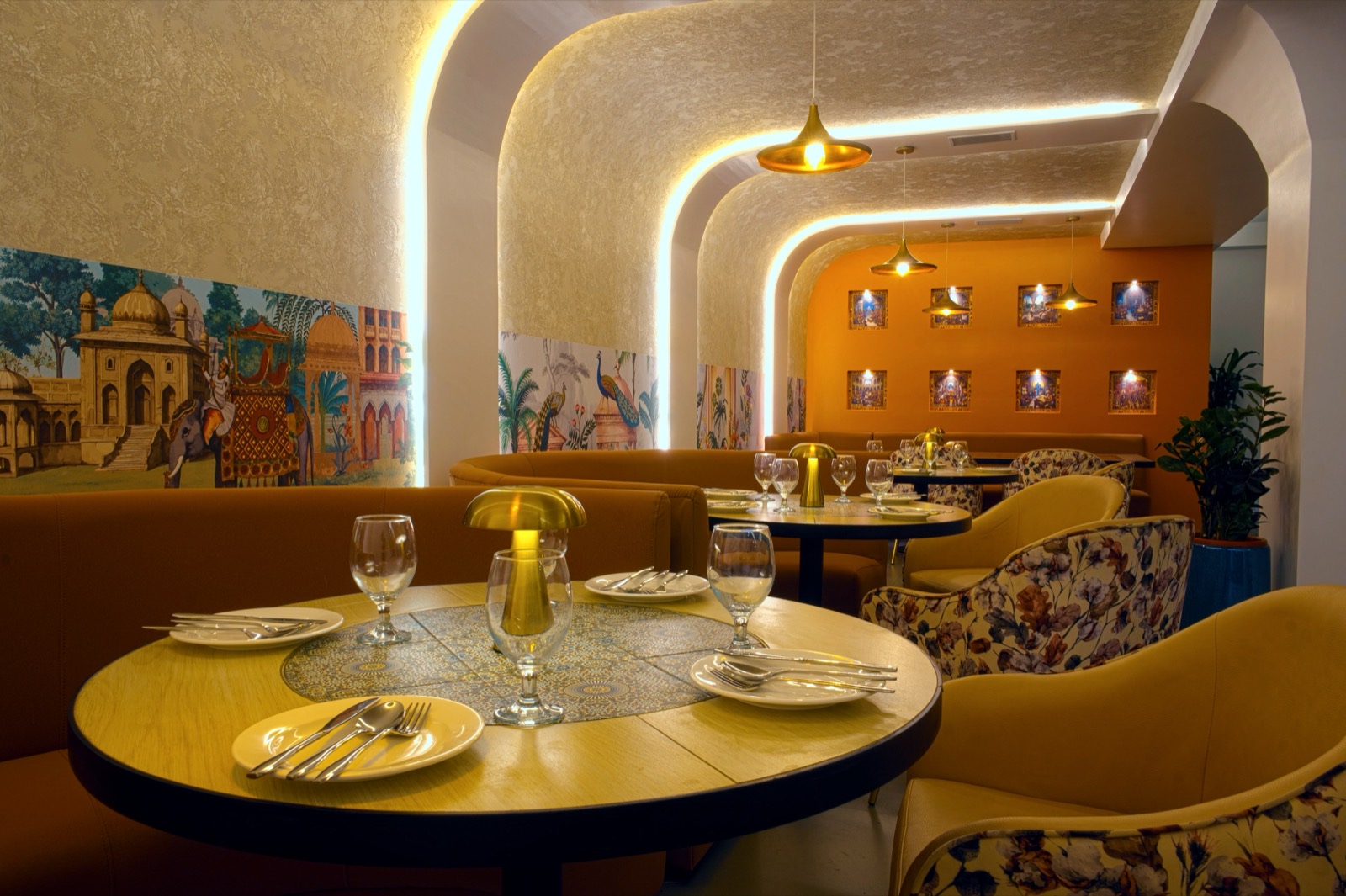 The indoor dining room at AZA Courtyard, with arched lit ceilings and Mughal murals